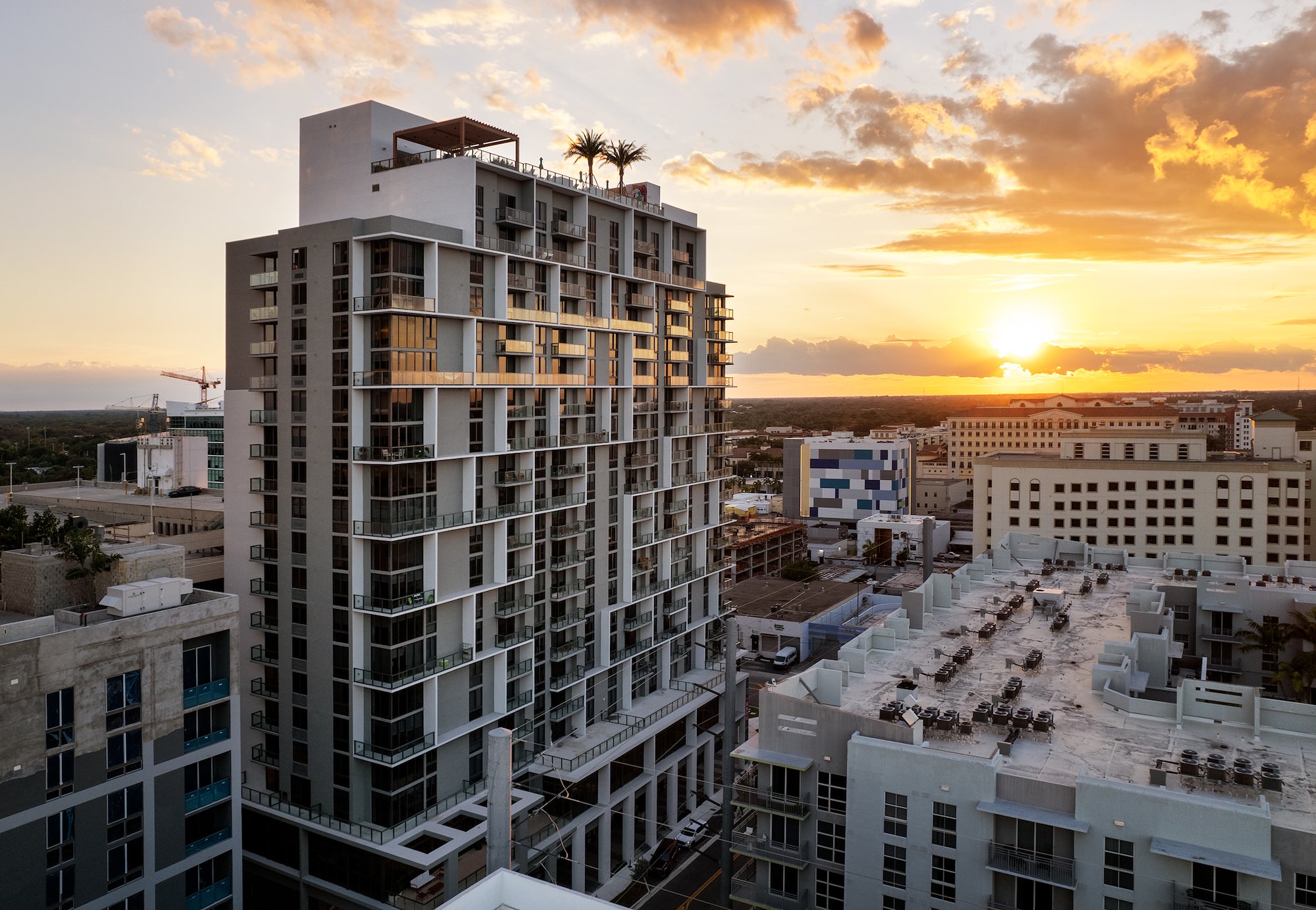a tall building with a sunset and city view in the background