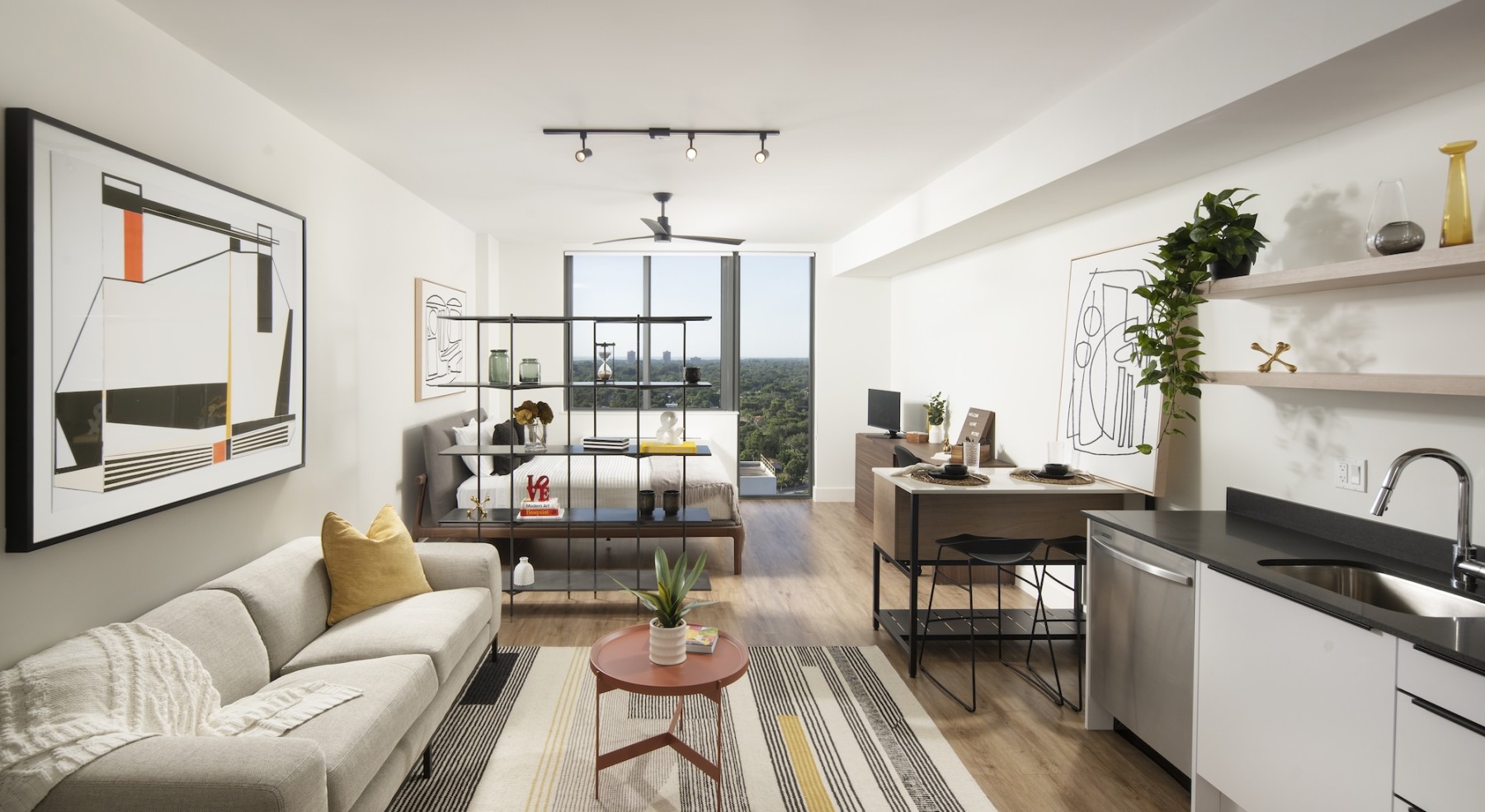 a studio apartment with a couch kitchen and view of a bedroom