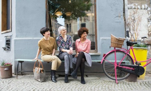 a group of women sitting on a bench with a bike