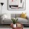 Modern living room with gray sofa, abstract art, bar cart, and red side table.