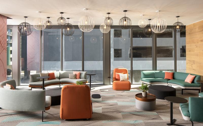 a lounge room with a couch and chairs and large windows