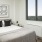 A bedroom with abstract art, gray headboard, and city view.