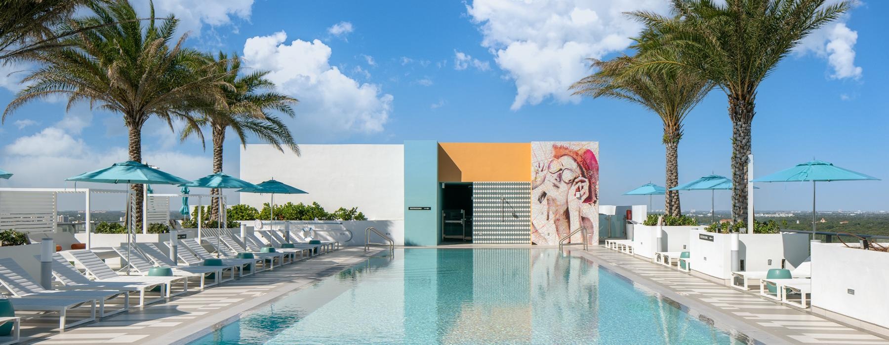 a swimming pool with lounge chairs and umbrellas next to it