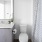 A bathroom with white fixtures, gray vanity, and patterned shower curtain.