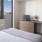 Modern apartment bedroom with desk, TV, and city view.