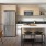 A kitchen with stainless steel appliances, light wood cabinets, black countertops, and a kitchen island with bar stools.