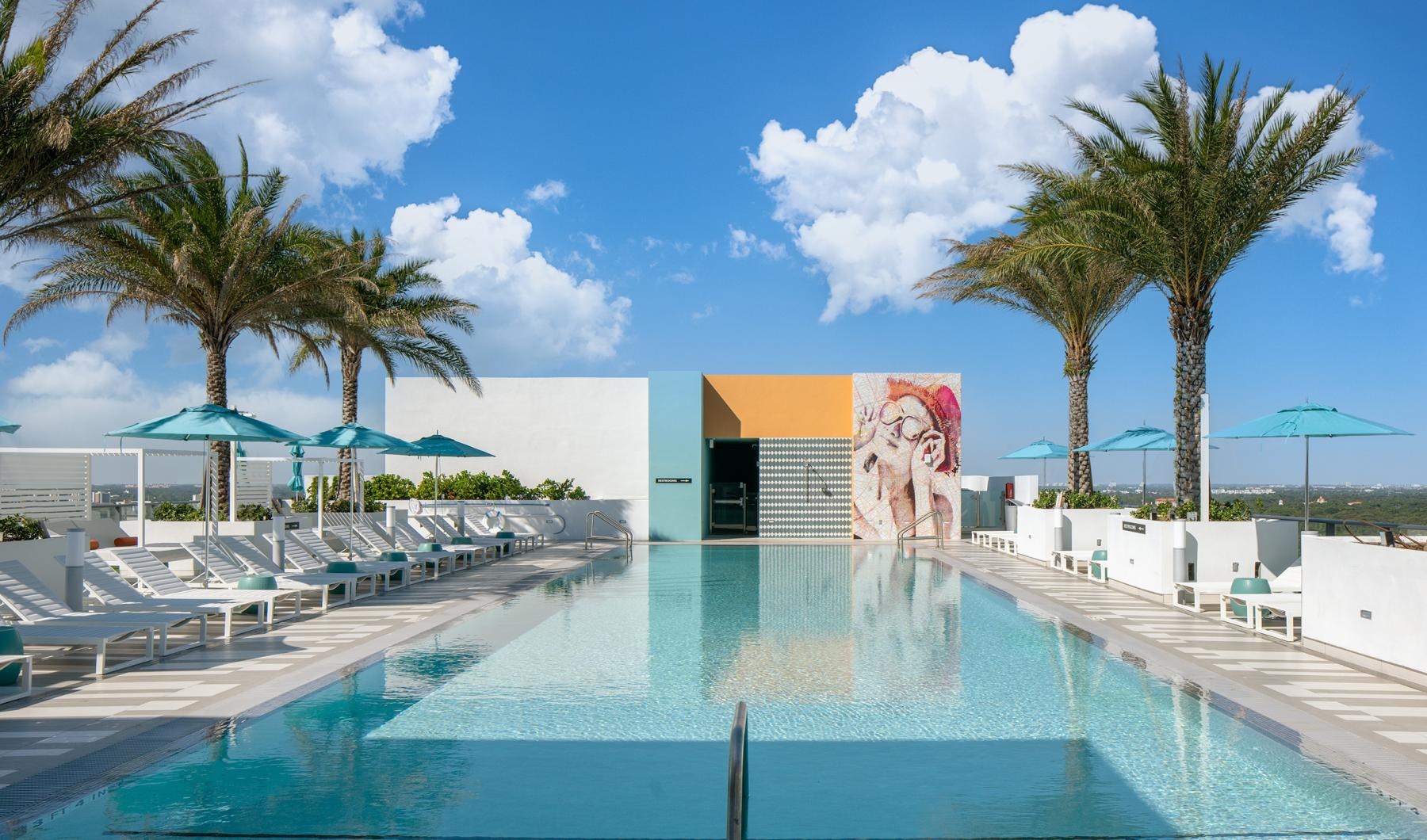 a swimming pool with lounge chairs and umbrellas next to it