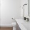 A bathroom with white walls, wood-look flooring, glass shower, toilet, and vanity with countertop accessories.